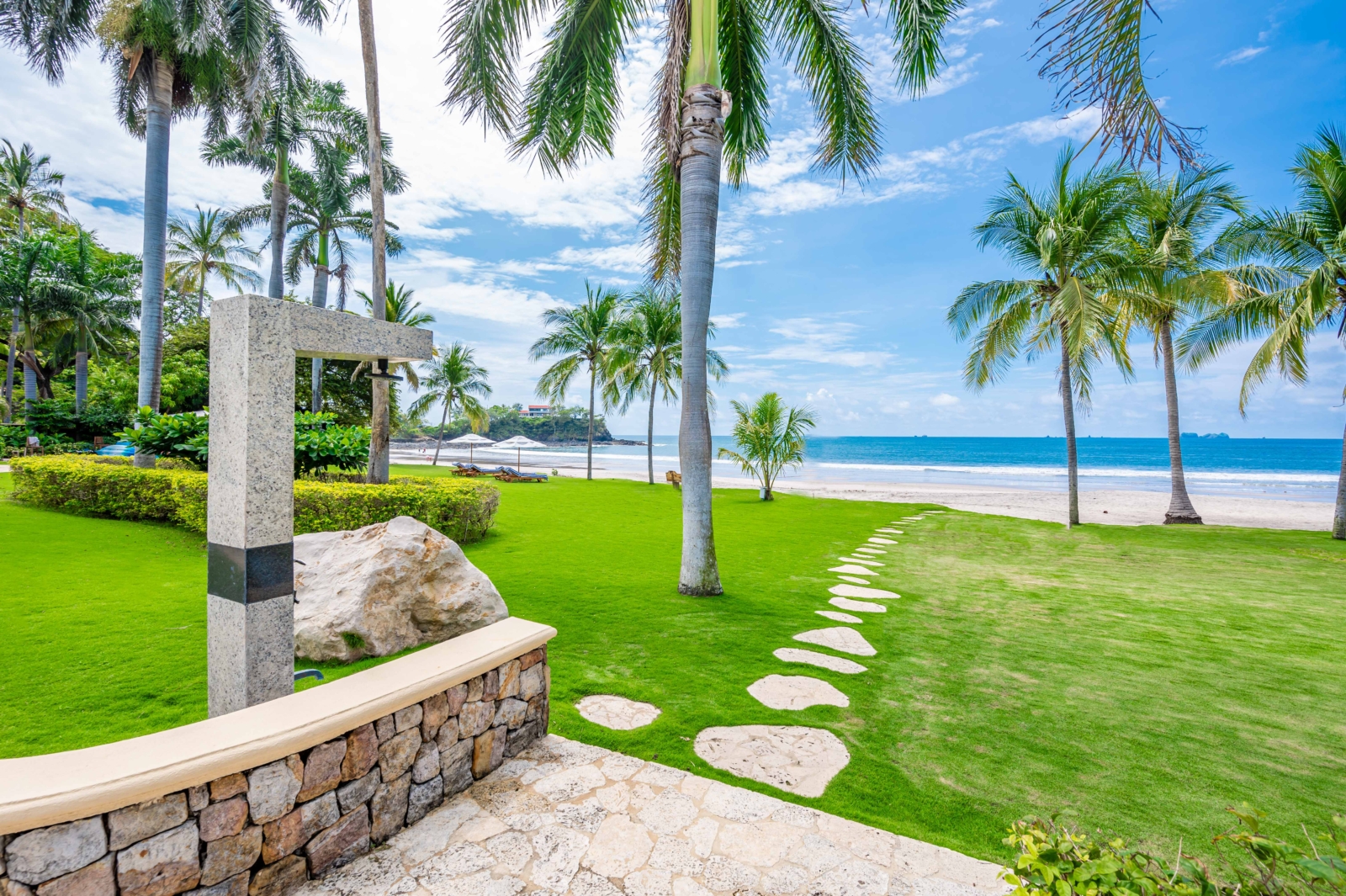 Scenic stone path leading to white-sand beach lined with palm trees in Costa Rica – Charity Ace luxury vacation package