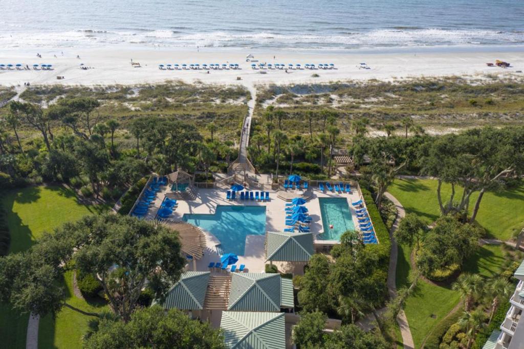 Aerial view of Hilton Head beachfront resort with pool, private beach access, and oceanfront lounge chairs.