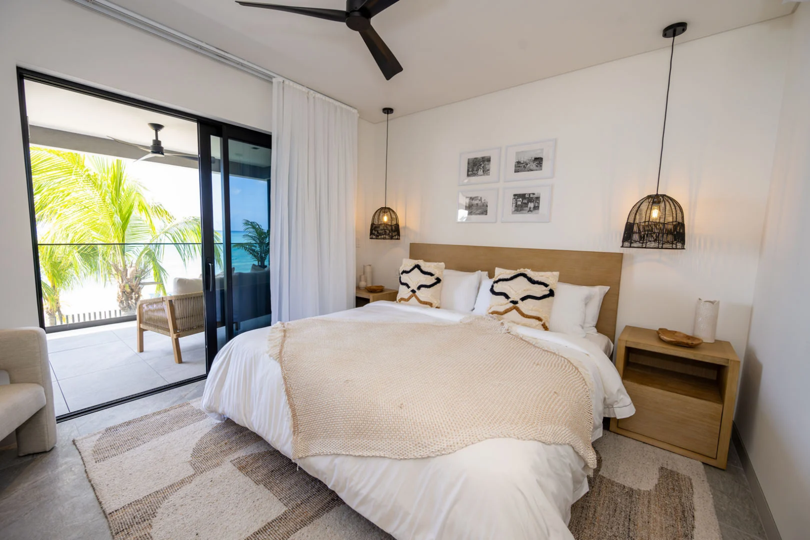 Elegant bedroom with king bed, natural textures, and private terrace overlooking palm trees and the Caribbean Sea