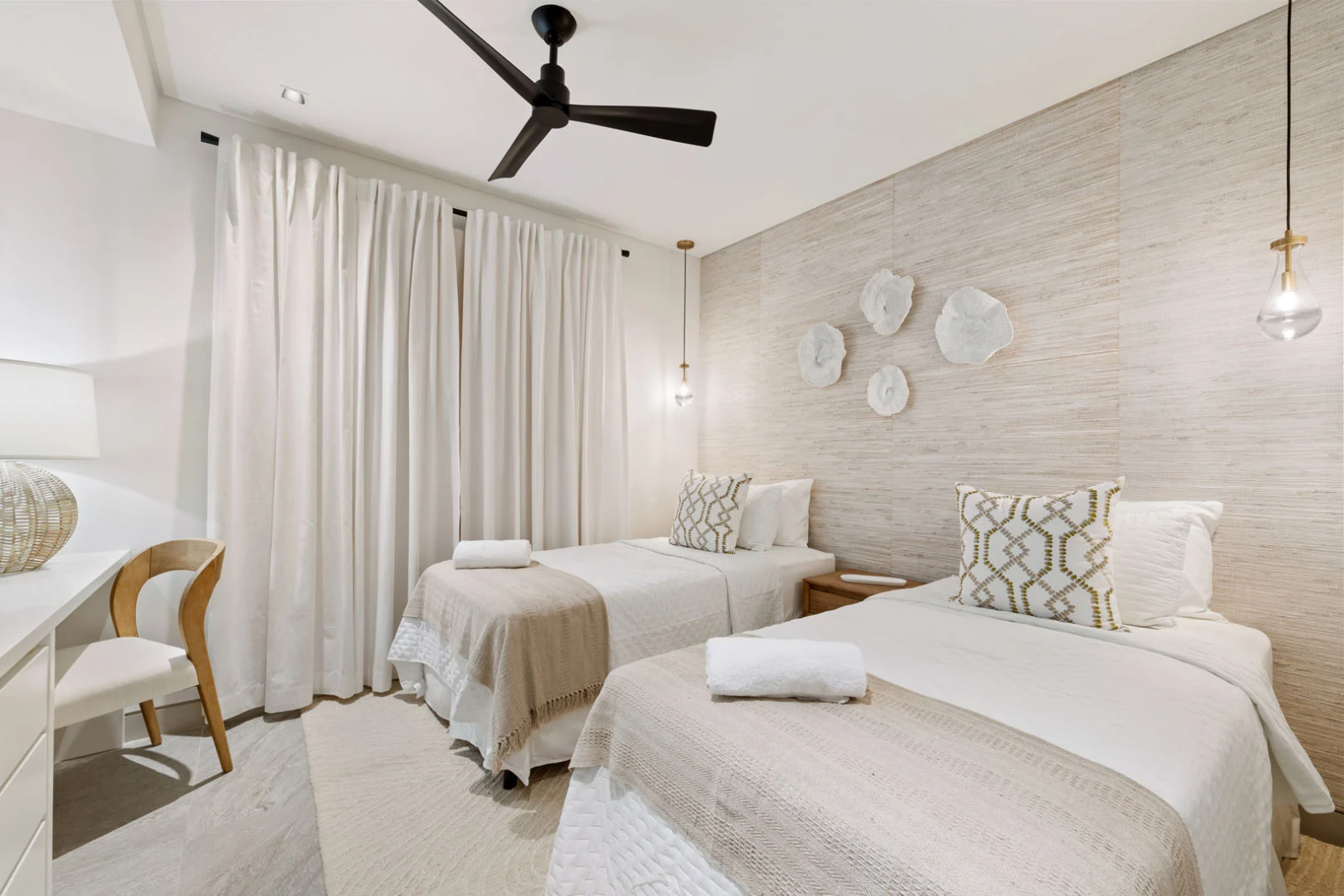 Neutral-toned guest room in Barbados apartment featuring twin beds and textured accent wall