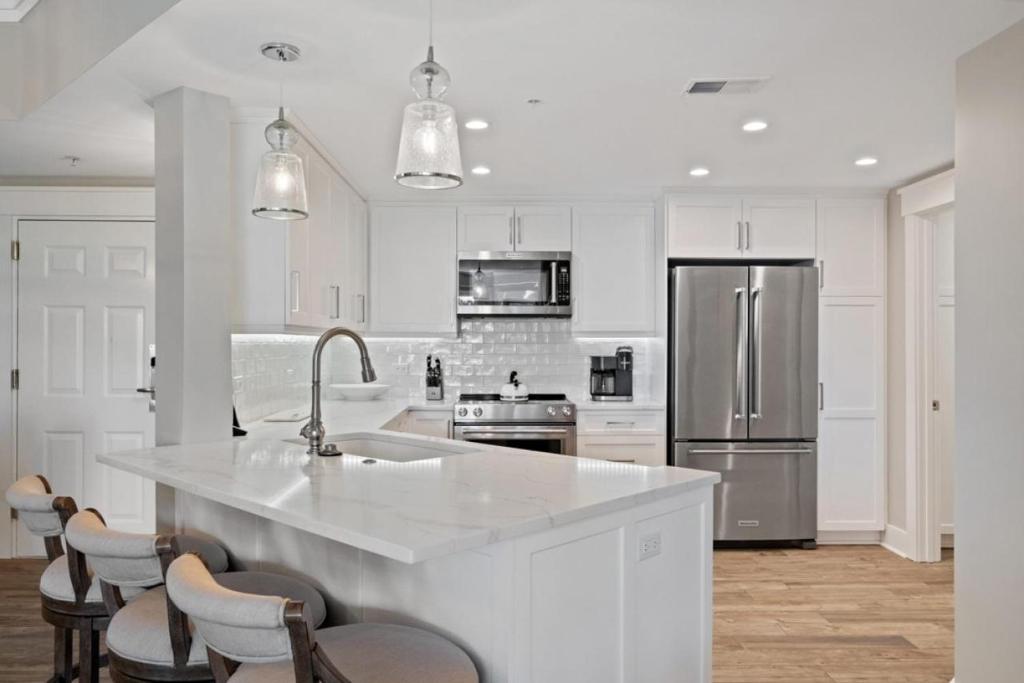Modern kitchen in Hilton Head villa with white cabinets, stainless steel appliances, and marble countertops