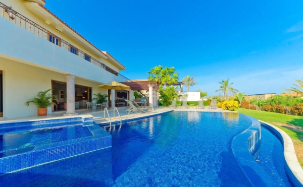 Luxury ocean-view villa in Los Cabos with private infinity pool, lounge chairs, and tropical landscaping under a clear blue sky