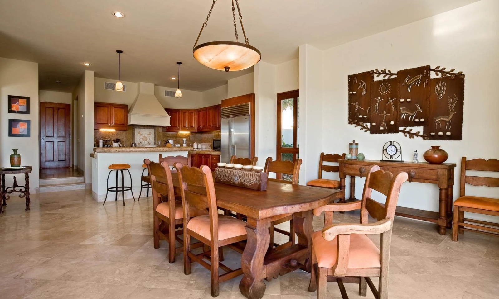 Gourmet kitchen and dining area in Los Cabos villa with rustic wood furniture, pendant lighting, and stainless steel appliances