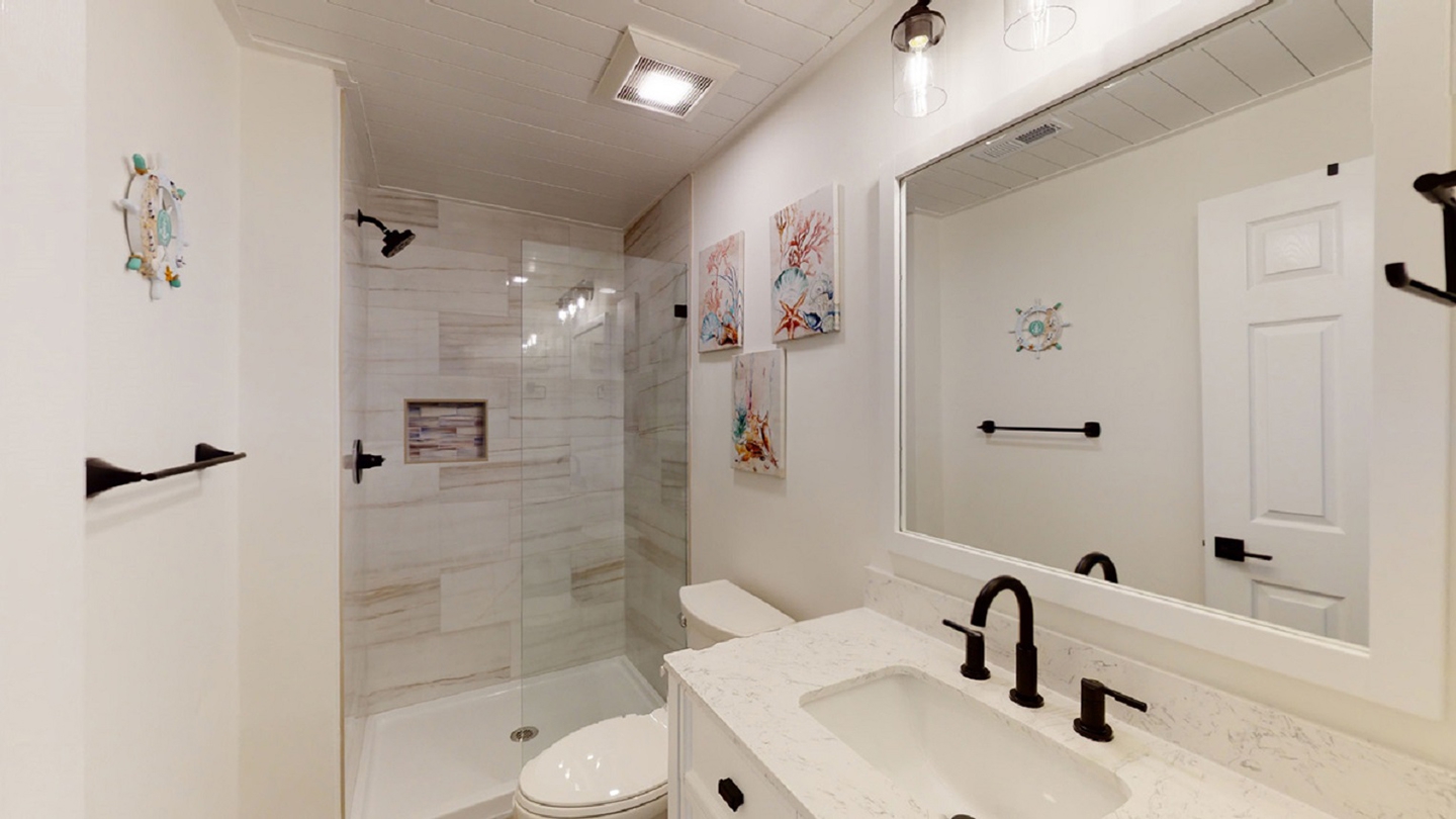 Modern bathroom with walk-in shower, marble countertops, and coastal decor in Hilton Head vacation rental