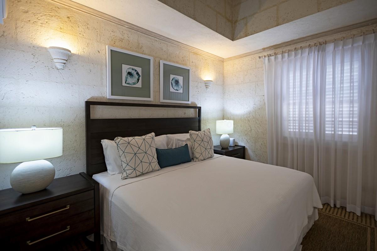 Stylish queen bedroom in a beachfront Barbados villa with geometric decor, soft lighting, and modern coastal design