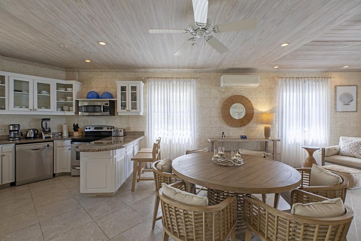 Fully equipped kitchen and dining space in a beachfront Barbados villa with white cabinetry and natural textures