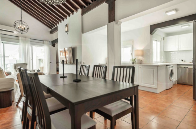 Elegant dining area with vaulted wooden ceilings and open-concept kitchen in a spacious Malaga apartment included in Charity Ace’s Spain auction package.