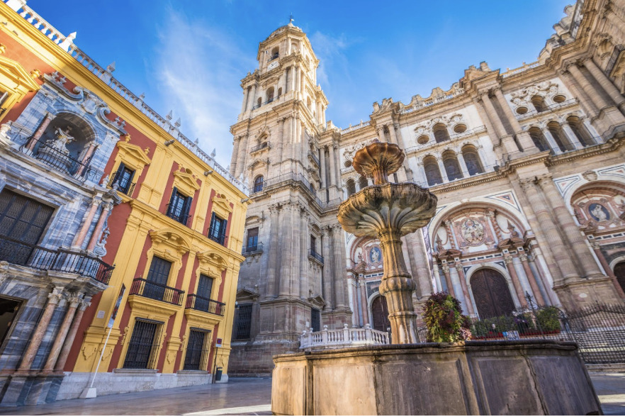 Stunning exterior of Malaga Cathedral with its historic fountain and colorful surrounding architecture—an iconic landmark near the Charity Ace Spain for 4 package accommodations.