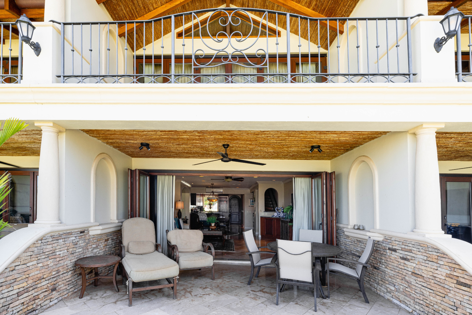 Private patio with cushioned lounge chairs beneath upper balcony of beachfront villa – Charity Ace Costa Rica auction package