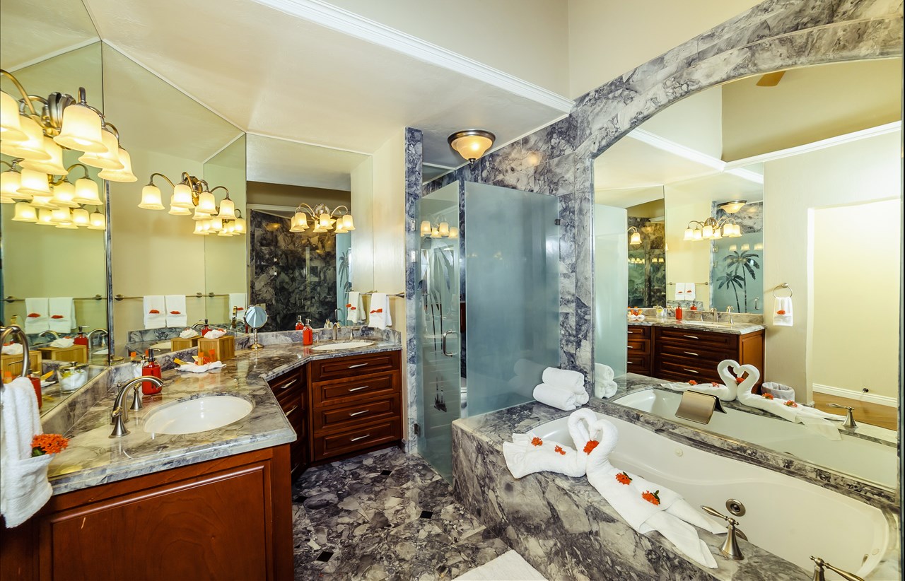 Elegant marble bathroom with double vanity, walk-in shower, and romantic towel swans – Charity Ace Costa Rica villa experience