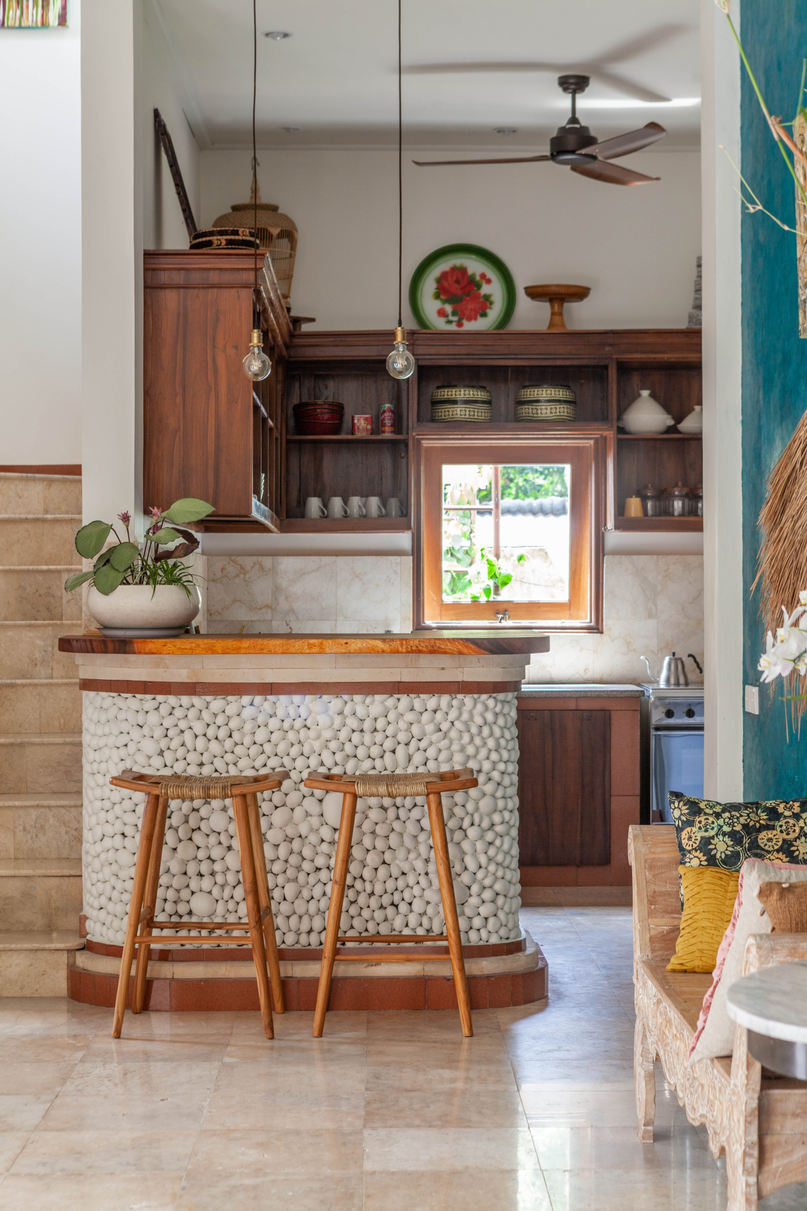 Modern kitchen with warm wooden tones and a decorative pebble counter in a Bali villa.